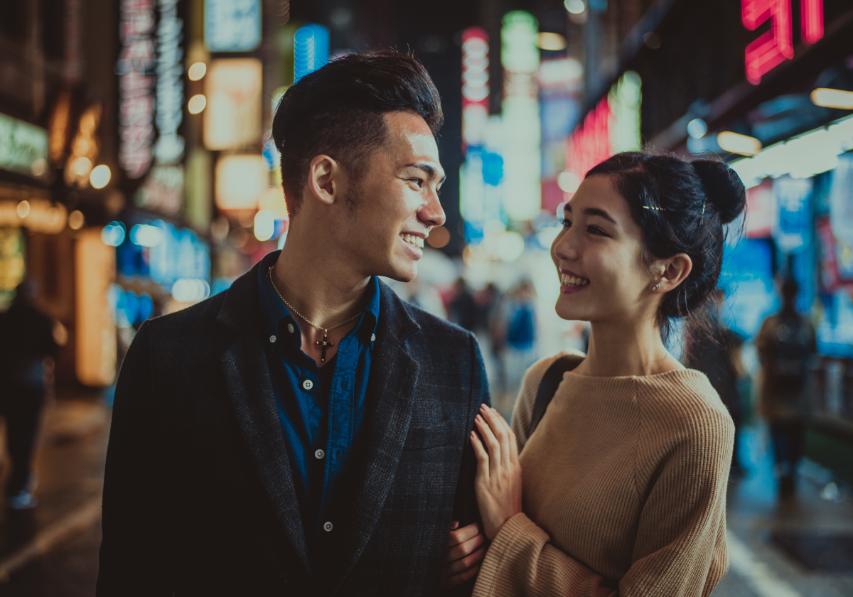 Photo of a man and woman walking down a street at night in Japan
