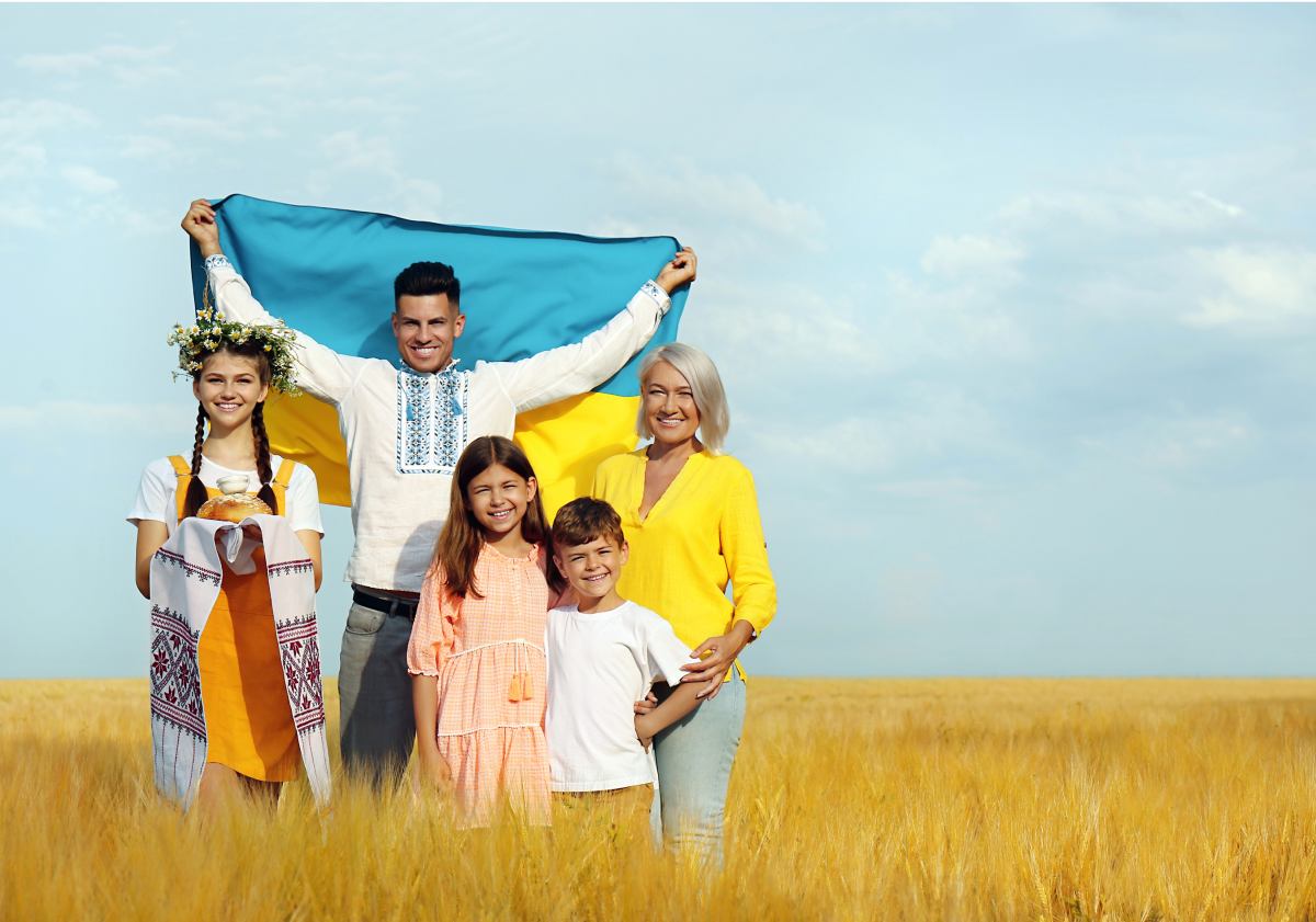 Photo of a family from Ukraine standing in a field holding a flag